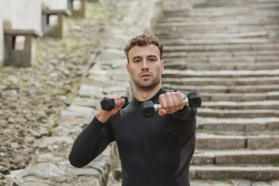 Man doing a dumbbell front raise outdoors