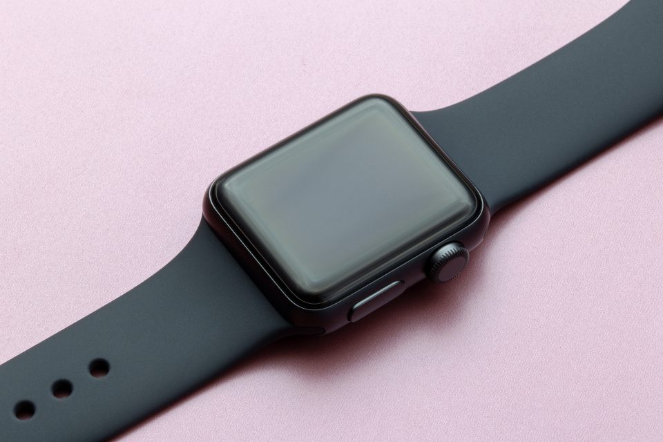 Smartwatch with a black band on a pink background