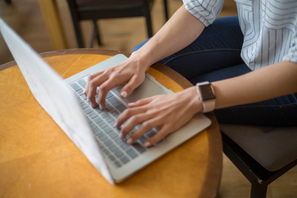 Woman typing on a laptop while wearing a smartwatch
