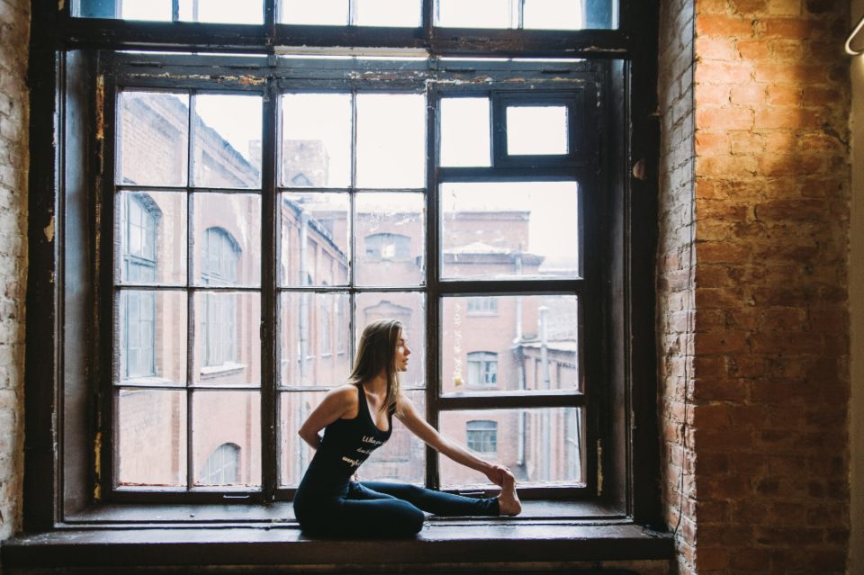 Woman stretching on a windowsill in a loft studio