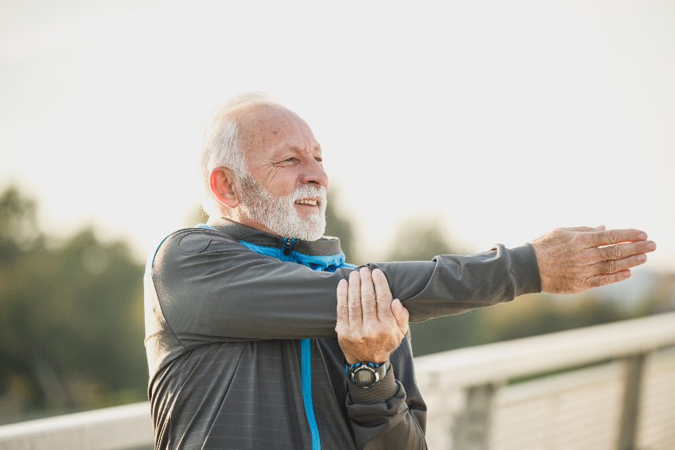Older man stretching his arm outdoors