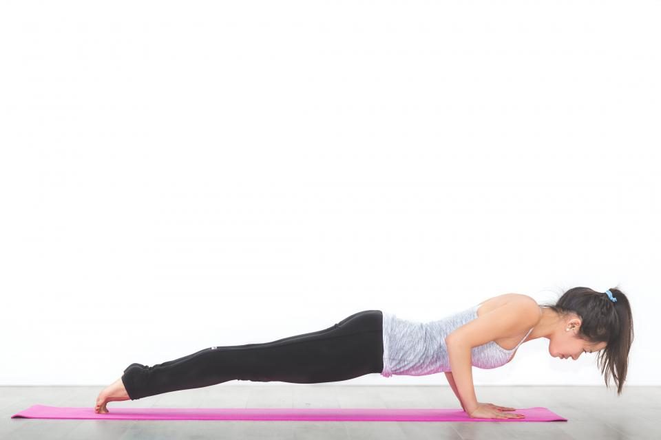 Woman in a plank position on a pink yoga mat