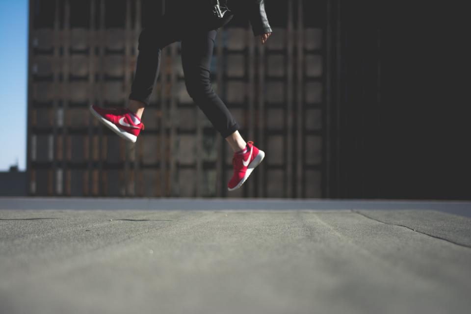 Runner mid-jump in red sneakers