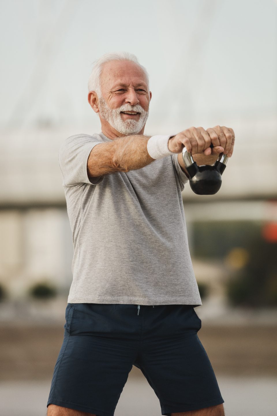 Older man swinging a kettlebell outdoors