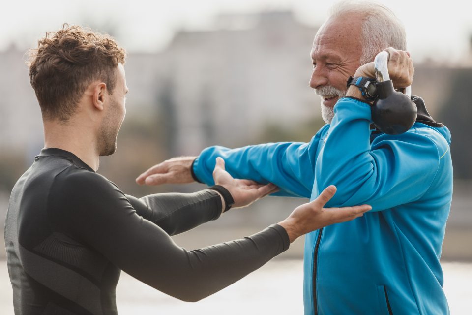 Trainer guiding a man through a kettlebell exercise